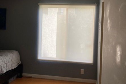 Bedroom window fully covered by custom pull down window shades, delivering privacy and a sleek, modern look.